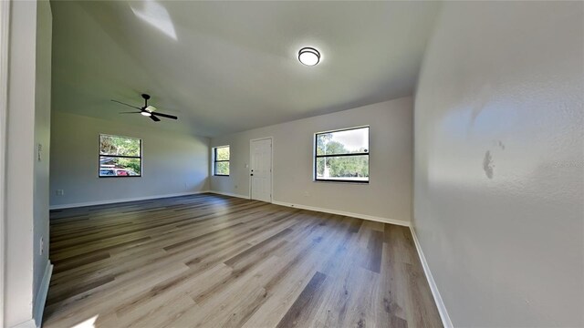 spare room featuring ceiling fan, light wood-type flooring, plenty of natural light, and vaulted ceiling