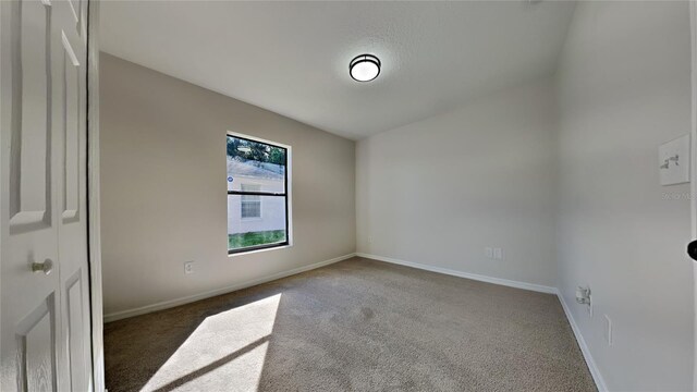 carpeted empty room with lofted ceiling