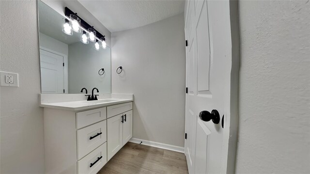 bathroom with a textured ceiling, hardwood / wood-style flooring, and vanity