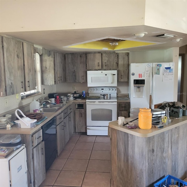 kitchen with kitchen peninsula, sink, white appliances, and tile patterned floors