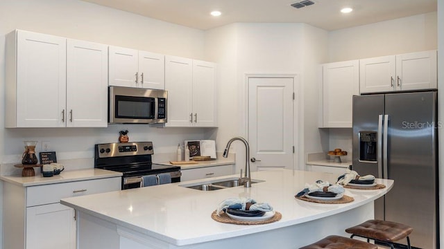 kitchen with an island with sink, white cabinetry, sink, and stainless steel appliances