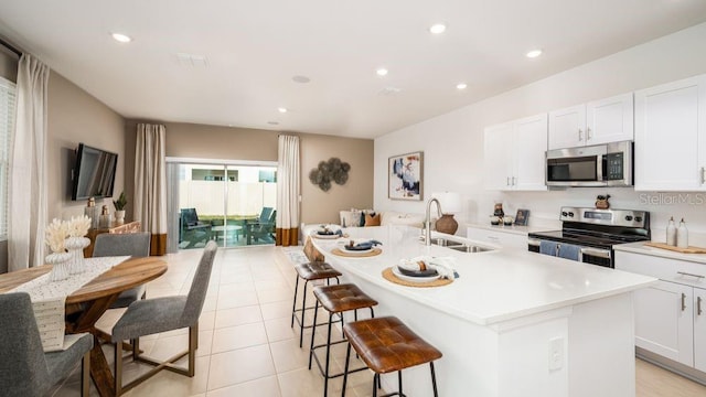 kitchen with a kitchen island with sink, sink, stainless steel appliances, and white cabinets