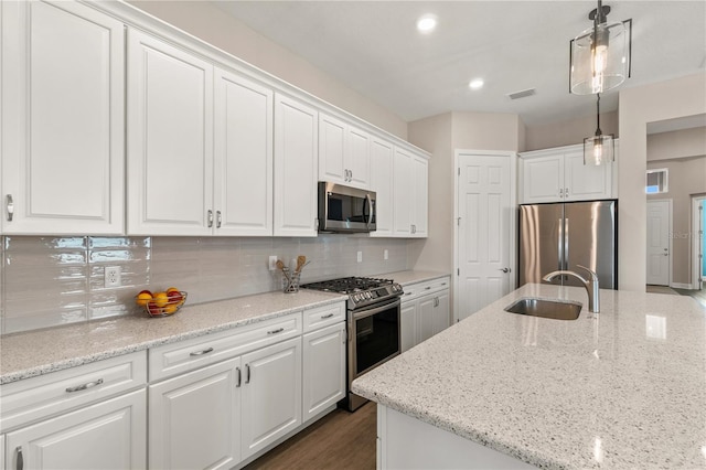 kitchen featuring light stone counters, sink, decorative light fixtures, white cabinetry, and appliances with stainless steel finishes