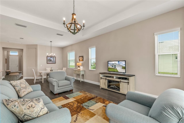 living room featuring an inviting chandelier, a raised ceiling, and dark hardwood / wood-style flooring