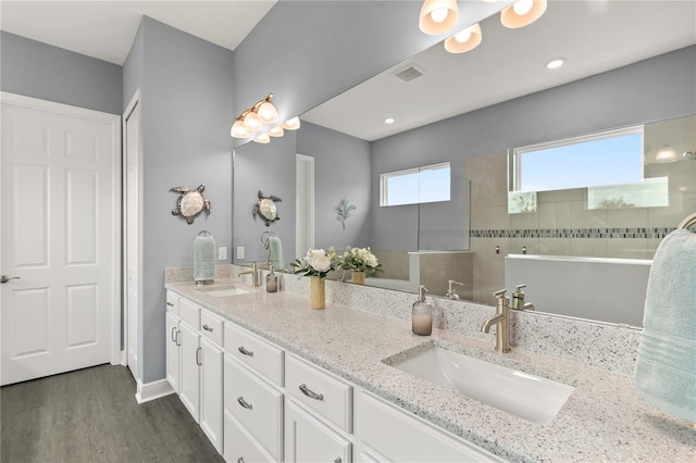 full bath featuring double vanity, a sink, a walk in shower, and wood finished floors