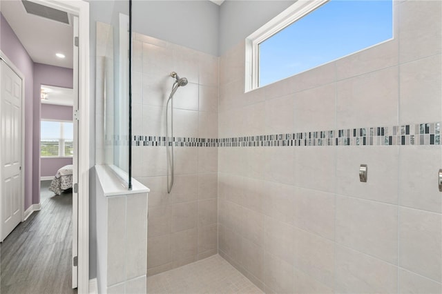 bathroom featuring a tile shower and wood-type flooring