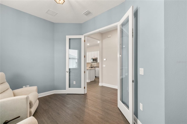 living area featuring dark wood finished floors, visible vents, and baseboards
