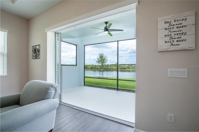 doorway to outside with wood finished floors, ceiling fan, and a water view