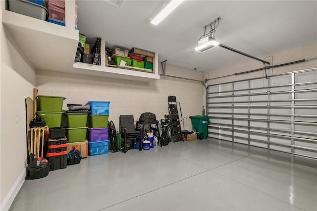 garage featuring a garage door opener and concrete block wall
