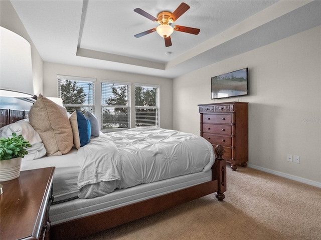 bedroom featuring a raised ceiling, ceiling fan, and carpet flooring