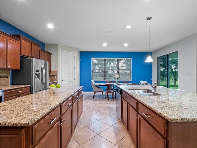 kitchen featuring an island with sink, appliances with stainless steel finishes, sink, and decorative light fixtures