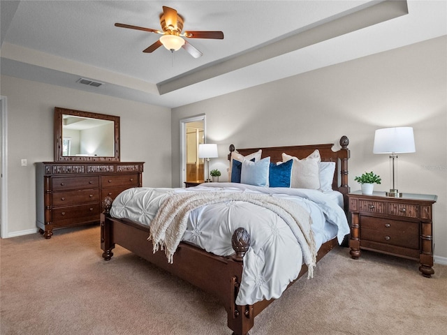 bedroom featuring light carpet, a tray ceiling, and ceiling fan