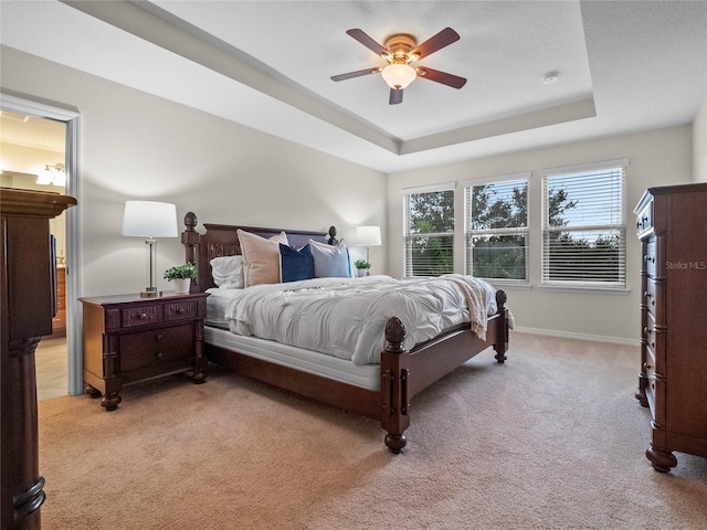 carpeted bedroom featuring ceiling fan and a raised ceiling