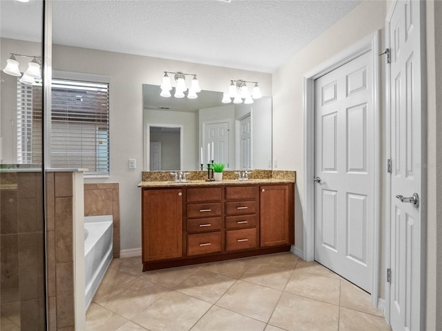 bathroom featuring tile patterned flooring, vanity, a textured ceiling, and a tub to relax in