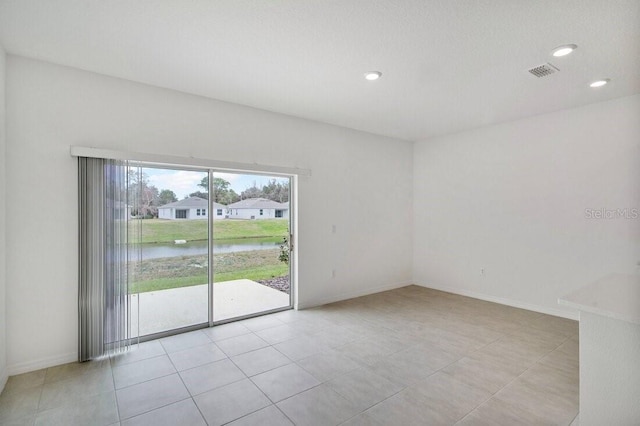 unfurnished room with recessed lighting, visible vents, a water view, and baseboards