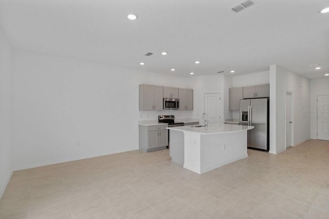 kitchen featuring appliances with stainless steel finishes, light countertops, gray cabinetry, and a sink