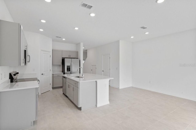 kitchen featuring visible vents, gray cabinetry, light countertops, appliances with stainless steel finishes, and a kitchen island with sink