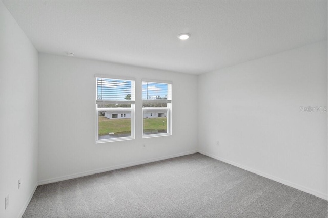 carpeted empty room featuring baseboards