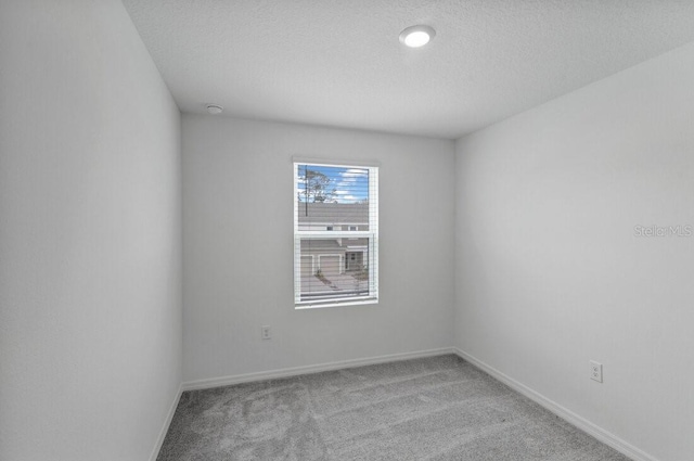 carpeted empty room featuring baseboards and a textured ceiling