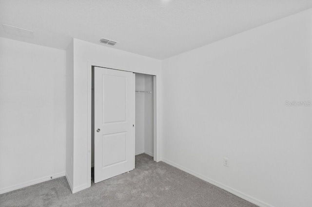 unfurnished bedroom featuring visible vents, baseboards, carpet, and a closet