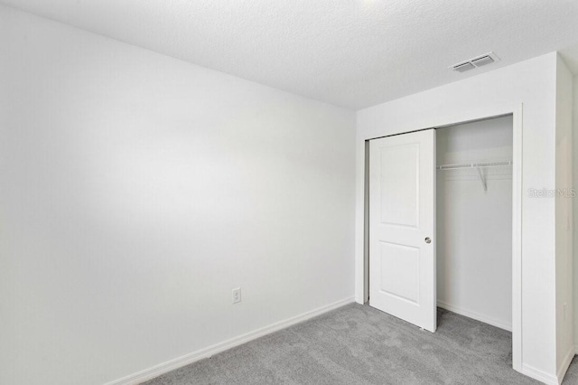 unfurnished bedroom featuring visible vents, baseboards, carpet flooring, a closet, and a textured ceiling