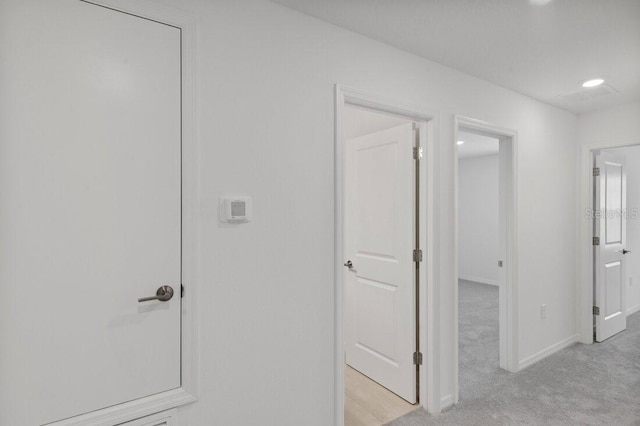 hallway with recessed lighting, light colored carpet, and baseboards