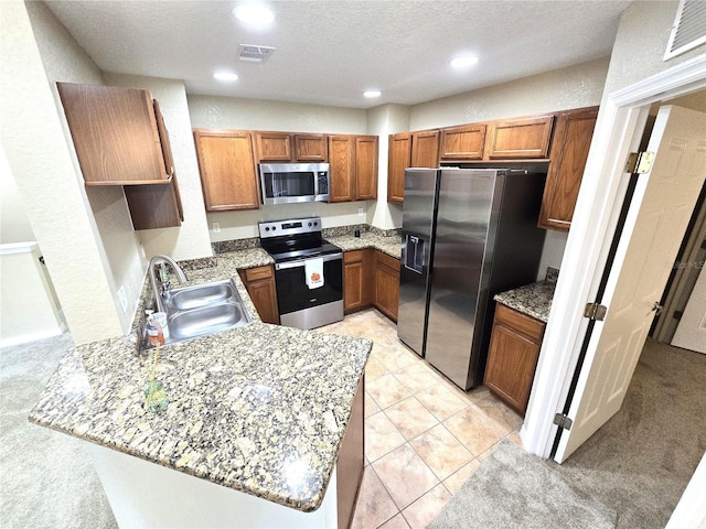 kitchen with light colored carpet, kitchen peninsula, appliances with stainless steel finishes, and sink