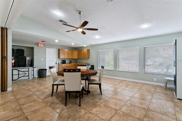 dining space with light tile patterned floors, a textured ceiling, vaulted ceiling, and ceiling fan