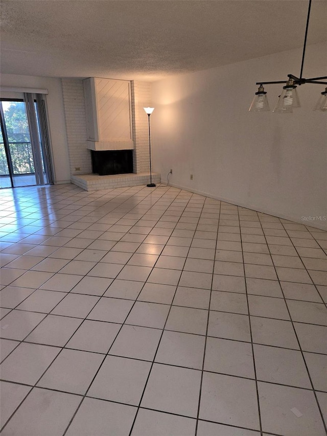 unfurnished living room with light tile patterned floors, a textured ceiling, and a brick fireplace