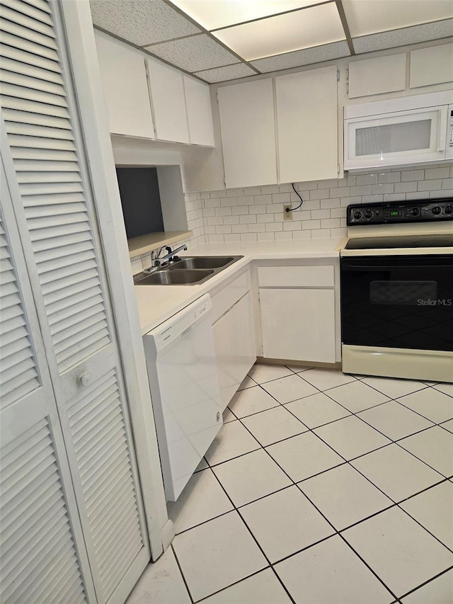 kitchen with white cabinetry, sink, light tile patterned floors, and white appliances