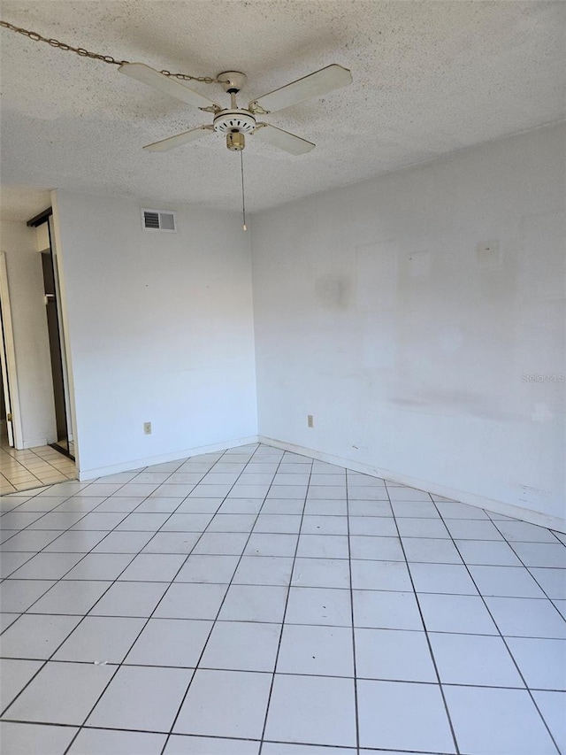 tiled empty room featuring a textured ceiling and ceiling fan