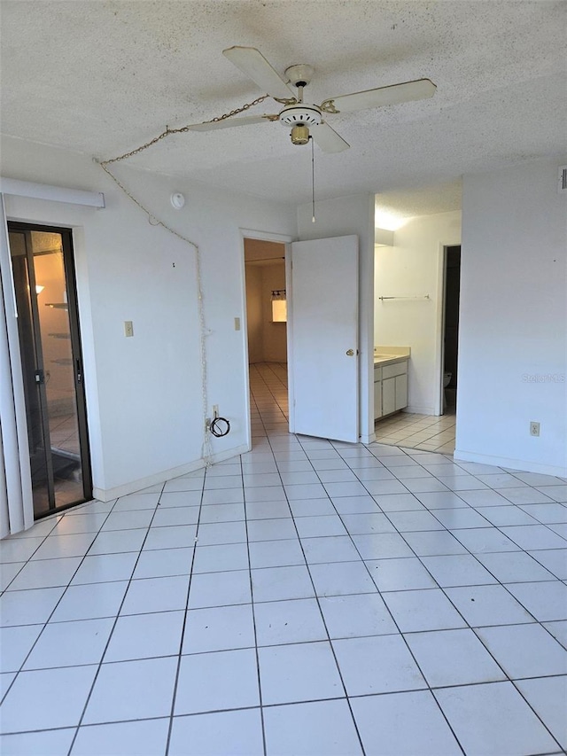 tiled empty room featuring ceiling fan and a textured ceiling