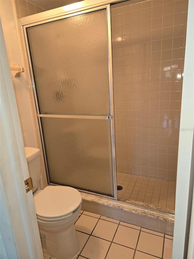 bathroom with tile patterned flooring, a shower with shower door, and toilet