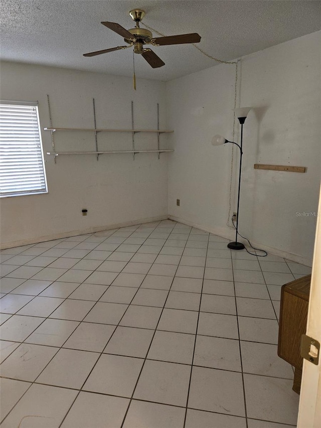 spare room with ceiling fan, light tile patterned floors, and a textured ceiling