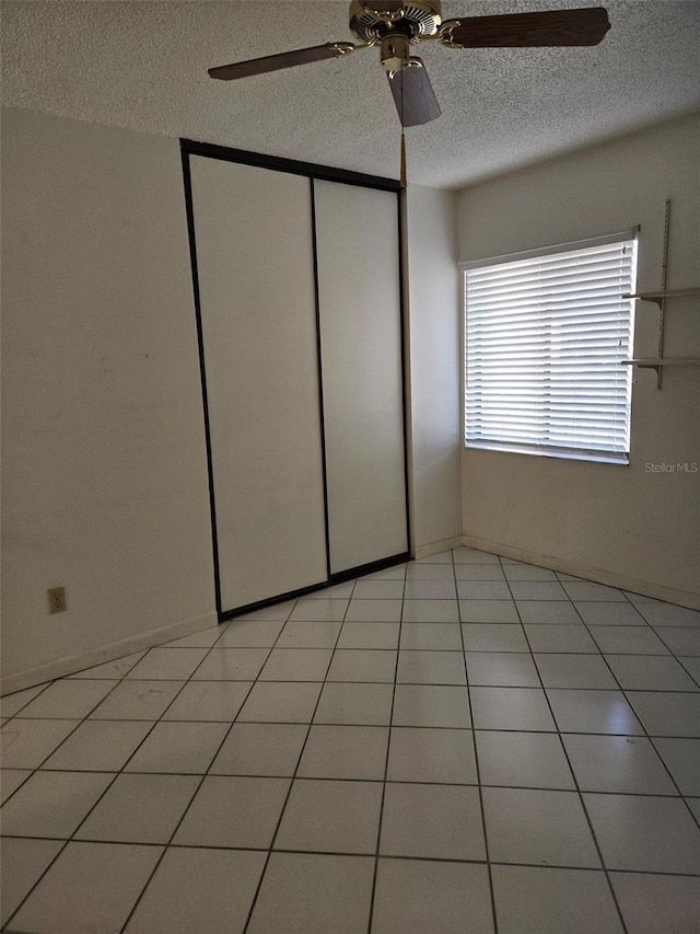 unfurnished bedroom with multiple windows, ceiling fan, a closet, and light tile patterned floors