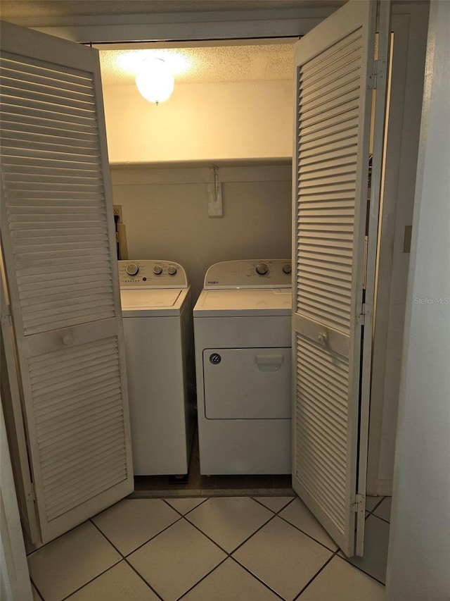 laundry area with washing machine and dryer and light tile patterned floors