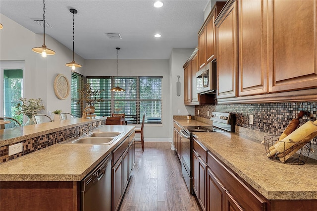 kitchen with an island with sink, appliances with stainless steel finishes, dark wood-type flooring, and a wealth of natural light