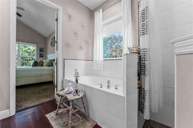 bathroom with wood-type flooring, a bathtub, vaulted ceiling, and ceiling fan