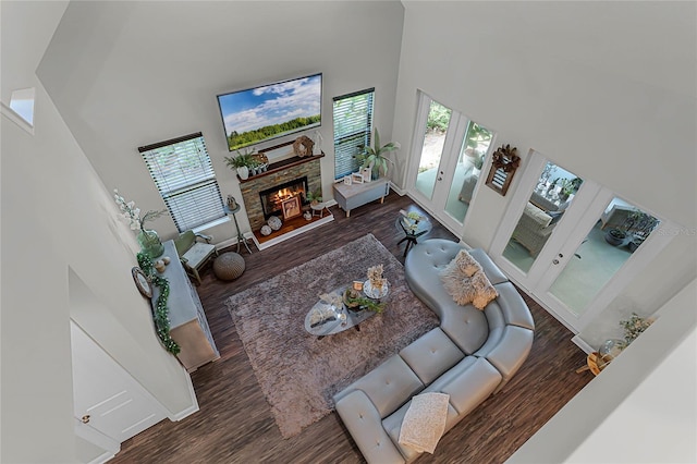 living room with a fireplace, a towering ceiling, and dark hardwood / wood-style floors