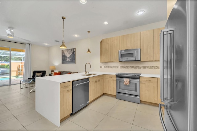 kitchen with hanging light fixtures, sink, kitchen peninsula, stainless steel appliances, and light brown cabinetry