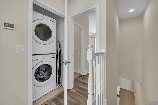 clothes washing area featuring stacked washer and clothes dryer and hardwood / wood-style flooring