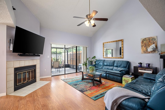 living room with high vaulted ceiling, a fireplace, light hardwood / wood-style floors, and ceiling fan