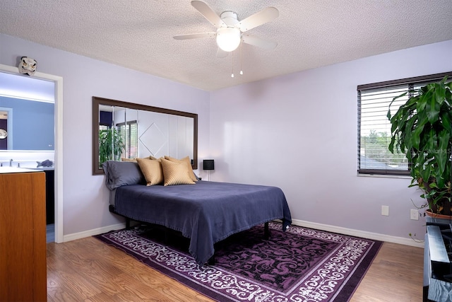 bedroom featuring ceiling fan, hardwood / wood-style flooring, and a textured ceiling