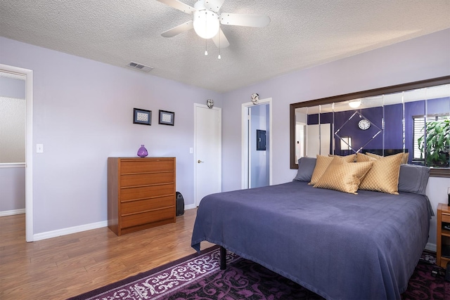 bedroom featuring ceiling fan, wood-type flooring, and a textured ceiling