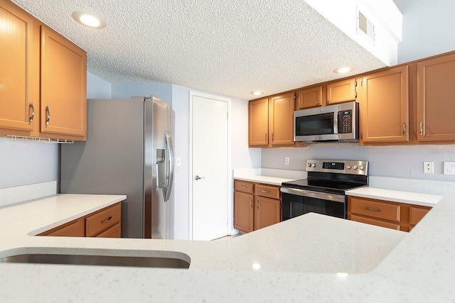 kitchen with appliances with stainless steel finishes, sink, and a textured ceiling