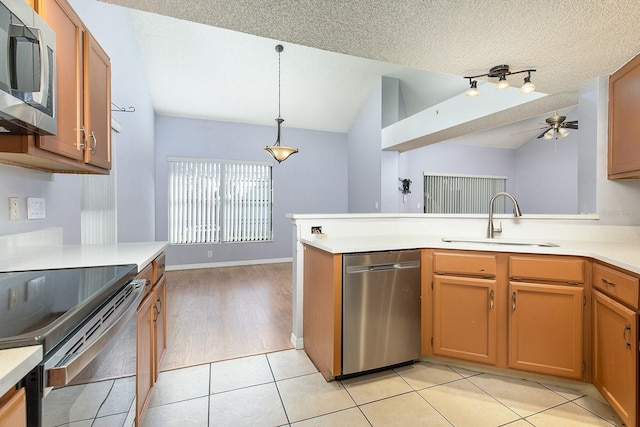 kitchen featuring decorative light fixtures, lofted ceiling, sink, kitchen peninsula, and stainless steel appliances