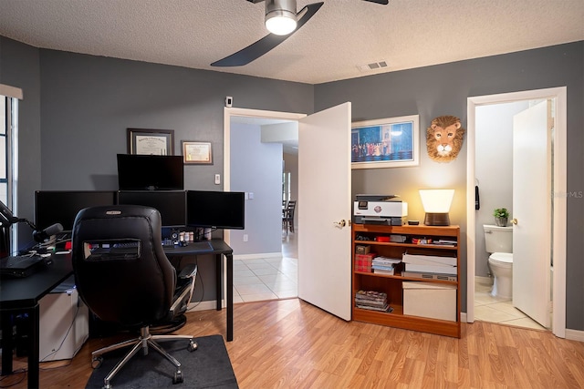 office featuring light wood-type flooring, a textured ceiling, and ceiling fan