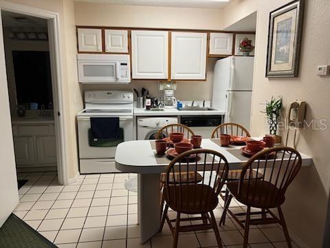 kitchen featuring light tile patterned flooring, white appliances, and white cabinetry