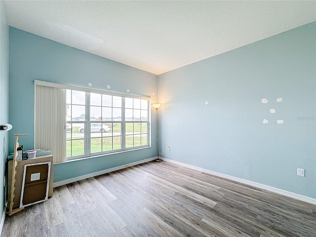 empty room featuring light wood-type flooring and a textured ceiling