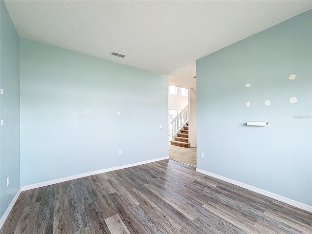 empty room with wood-type flooring and a textured ceiling